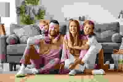 stock photo of mother and father with two children sitting on floor in front of sofa